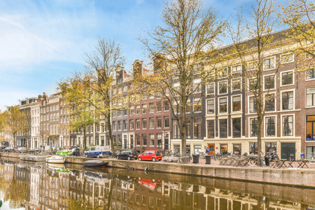 some buildings and boats on a canal in the middle of an urban area, with trees reflected in the waterのeditorial素材