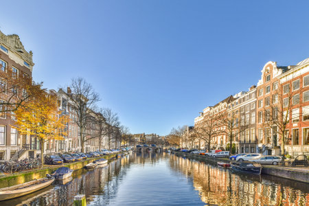 a canal with boats on the water and buildings in the background, as seen from across the river there is a clear blue skyのeditorial素材