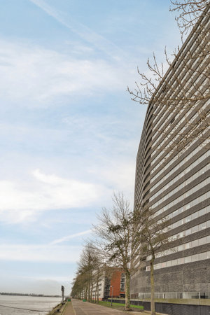 Amsterdam, Netherlands - 10 April, 2021: an office building on the waters edge with trees and buildings in the fore - lit area to the leftのeditorial素材