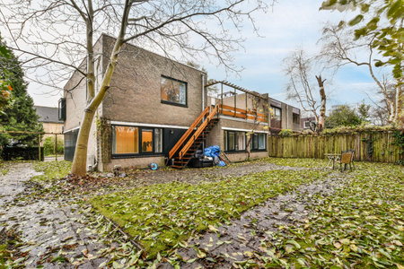 a house that has fallen leaves on the ground in front of it, with a ladder up to the roof