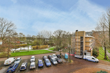 a parking lot with cars parked in it and some buildings on the other side of the road, as seen from...