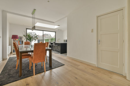 a dining room with hardwood flooring and white walls in the background is an open door that leads to a patioのeditorial素材