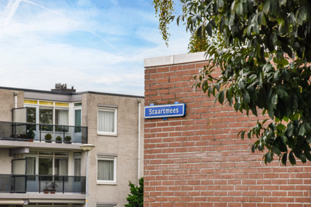 a street sign on the side of a brick wall in front of a building with trees and bushes around itのeditorial素材