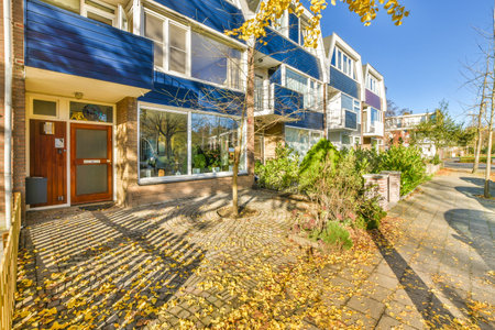 an outside area with leaves on the ground and buildings in the background that are blue, white, and...
