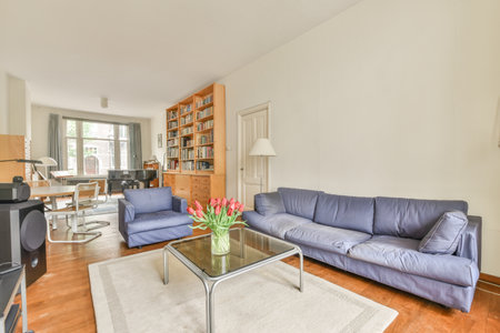 a living room with blue couches and a glass coffee table in the center of the room is white walls