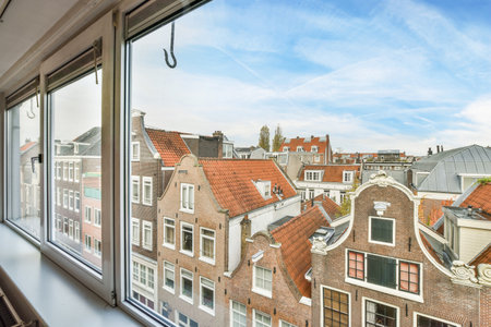 Amsterdam, Netherlands - 10 April, 2021: a view from the window of an apartment building with red roofs and blue sky in the background, as seen on a sunny dayのeditorial素材