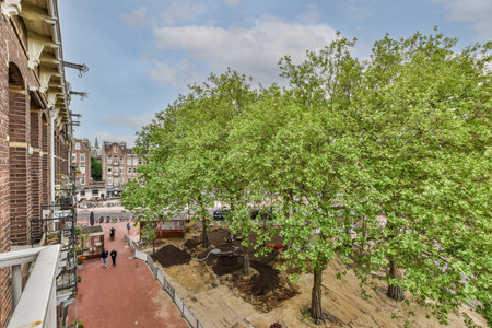 Amsterdam, Netherlands - 10 April, 2021: a tree that is in the middle of an urban area, with people walking on the sidewalk and buildings behind itのeditorial素材
