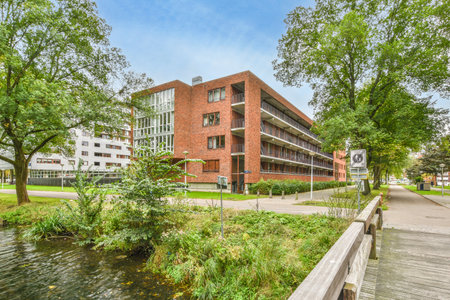 a brick building with trees in the front and water flowing from its side to the other buildings on either sideのeditorial素材