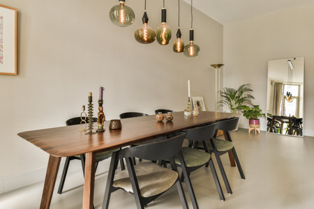 Amsterdam, Netherlands - 10 April, 2021: a dining table and chairs in a room with light fixtures on the wall behind it, there is an art work hanging aboveのeditorial素材