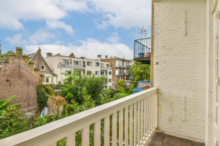 Amsterdam, Netherlands - 10 April, 2021: a balcony with trees and houses in the background on a sunny day, taken from an apartment window looking out onto the streetのeditorial素材