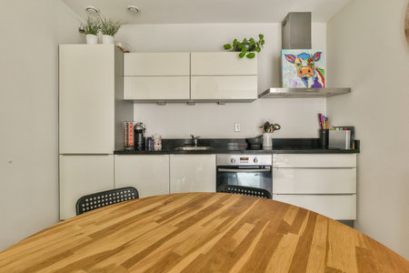 a kitchen and dining area in a small apartment with white cabinets, wood flooring and black countertops on the wallのeditorial素材
