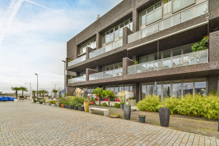 Amsterdam, Netherlands - 10 April, 2021: an apartment building with plants in the front and cars...