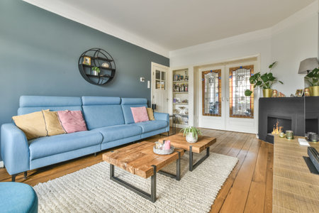 a living room with blue couch and wooden coffee table in the room is decorated with plants, pots and...