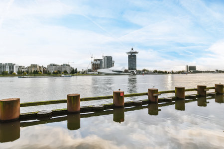 Amsterdam, Netherlands - 10 April, 2021: some buildings and water in the middle of a body of water with blue skies above it on a sunny dayのeditorial素材