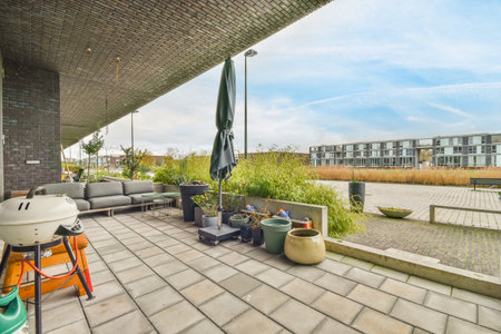 Amsterdam, Netherlands - 10 April, 2021: an outdoor living area with patio furniture and potted plants on the ground, surrounded by brick walls and blue skyのeditorial素材