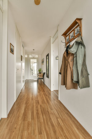 Amsterdam, Netherlands - 10 April, 2021: a long hallway with wood flooring and coat rack hanging on the wall in front of the door to the rightのeditorial素材
