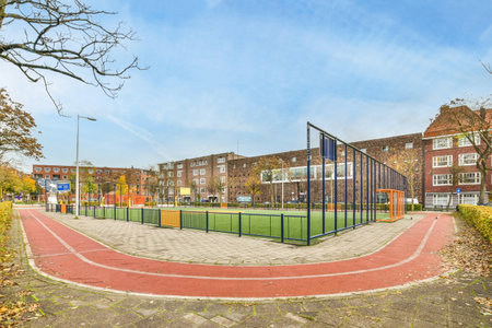 a tennis court in the middle of an urban area with trees and buildings on either side, blue sky...