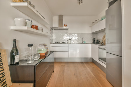 a kitchen with wood flooring and white appliances on the wall behind it is an open door that leads to another roomのeditorial素材