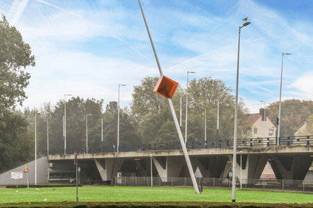 Amsterdam, Netherlands - 10 April, 2021: a bridge that is in the middle of a park with trees on both sides and an orange flag flying high above itのeditorial素材