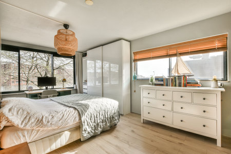 a bedroom with a bed, dresser and television set in the corner window is looking out to the trees outsideのeditorial素材