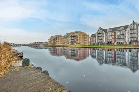 Amsterdam, Netherlands - 10 April, 2021: a body of water with buildings in the background and blue sky above it, as seen from across the riverのeditorial素材