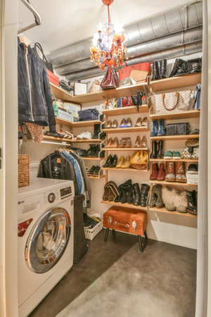 a laundry room with lots of clothes hanging on the wall and a washer in the corner next to itのeditorial素材