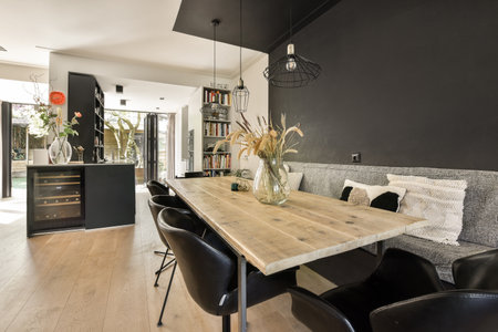 a dining room with wood flooring and black walls in the background, there is a wooden table...