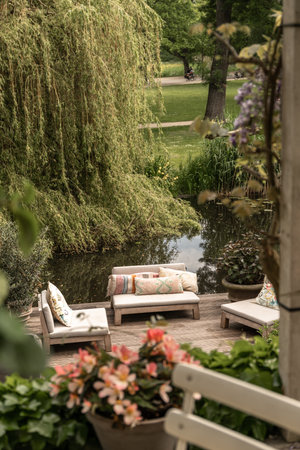 an outdoor living area with couches, tables and flowers on the deck in the background is a large willow treeのeditorial素材