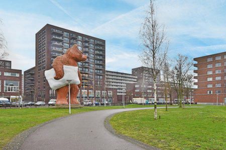 a bear statue on the side of a road in front of an apartment building with trees and buildings behind itのeditorial素材