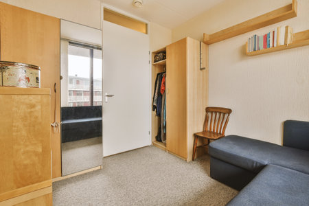 Amsterdam, Netherlands - 10 April, 2021: a living room with a couch, chair and bookshel in front of the door that leads to another roomのeditorial素材