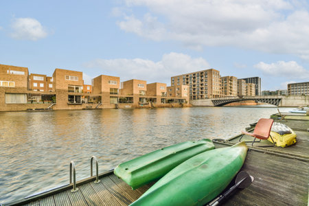 some boats docked on the water in front of an apartment complex with buildings and a bridge over the waters edgeのeditorial素材