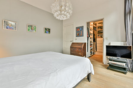 Amsterdam, Netherlands - 10 April, 2021: a bedroom with white walls and wood flooring on the wall, there is a television in the corner of the roomのeditorial素材