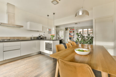Amsterdam, Netherlands - 10 April, 2021: a kitchen and dining area in a house with white walls, wood flooring and an island table surrounded by brown leather chairsのeditorial素材