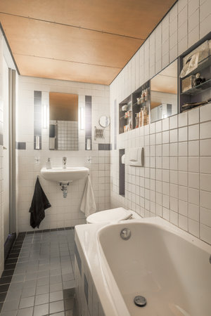 a bathroom with a bathtub and mirror on the wall next to the tub that is in front of the sinkのeditorial素材