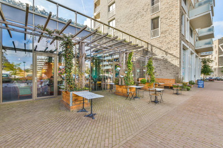 an outside area with tables and chairs on the sidewalk in front of a building that is made out of brickのeditorial素材