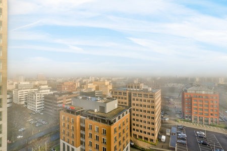 Amsterdam, Netherlands - 10 April, 2021: a city with buildings in the background and cars parked on the street below, as seen from an overcasted windowのeditorial素材