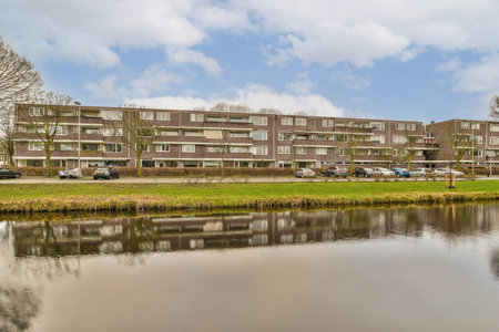 an apartment complex with cars parked in the parking lot next to the water and trees on the other side of the buildingの写真素材