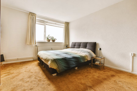 a bedroom with a bed, chair and lamp on the floor in front of a window that looks out to the outside