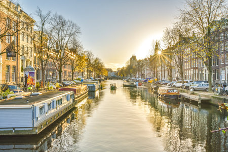 a canal with boats in the water and buildings on both sides, as seen from across the waterway at sunsetのeditorial素材