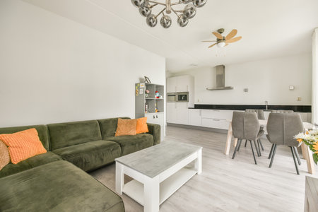 a living room with green couches and orange pillows on the sofa is next to an open kitchen area in the roomのeditorial素材