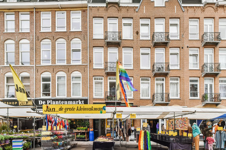 Amsterdam, Netherlands - 10 April, 2021: an outdoor market in front of a large brick building with lots of people shopping and selling items on the streetのeditorial素材
