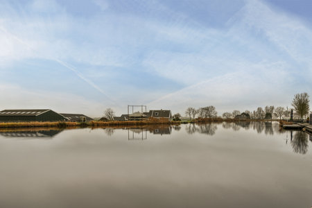 Amsterdam, Netherlands - 10 April, 2021: the sky and clouds over a body of water with houses on either side, as seen from across the riverのeditorial素材