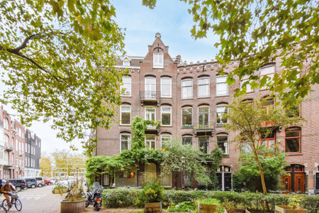 Amsterdam, Netherlands - 10 April, 2021: an apartment in the netherlands with lots of plants and trees on either side, there is a bicycle parked next to itのeditorial素材