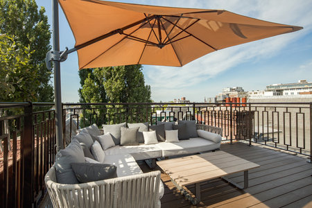 an outdoor living area with patio furniture and umbrellas on the balcony overlooking the cityscapearron comのeditorial素材