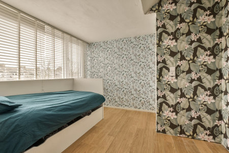 a bedroom with floral wallpaper on the walls and wooden flooring in front of bed, window blinds...