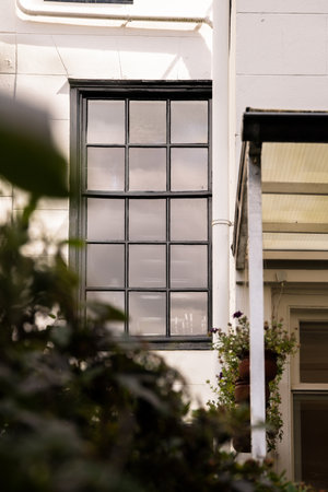Amsterdam, Netherlands - 10 April, 2021: a building with a clock on its side and some plants in the fore - sways behind themのeditorial素材