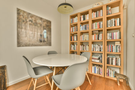 a room with bookshels on the wall and a white table in front of it, surrounded by wooden shelvesのeditorial素材