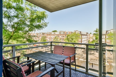 a balcony with two chairs and a table in front of the glass door that leads to an outdoor patio areaのeditorial素材