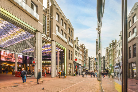 Amsterdam, Netherlands - 10 April, 2021: a city street with people walking on the sidewalks and buildings in the background, as seen through a glass windowのeditorial素材
