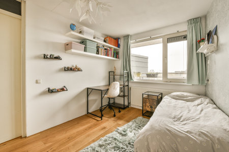 a bedroom with a bed, desk and books on shelves above the bed is in front of an open windowのeditorial素材